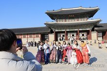 Foreign tourists take a group photo in front of the royal Gyeongbok Palace in central Seoul on Dec. 19, 2024. (Yonhap)