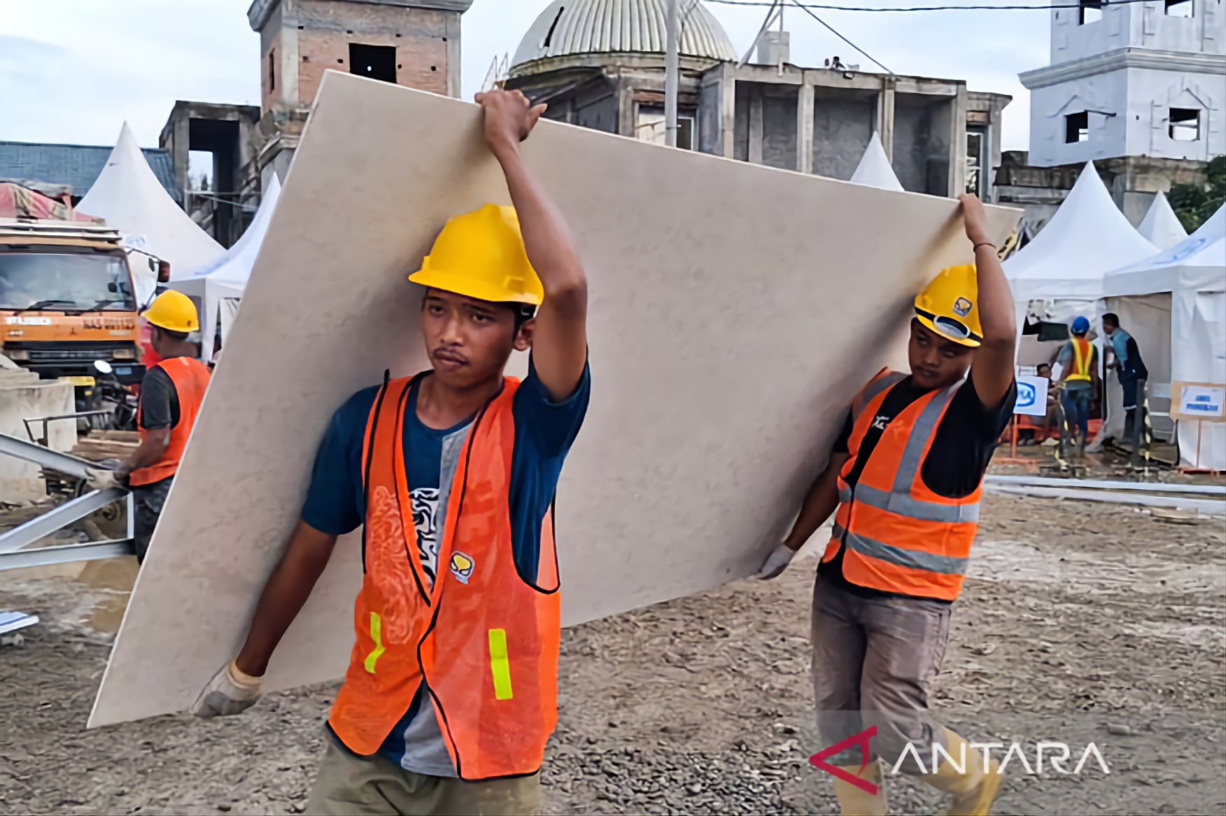 Workers carry building materials at a construction site for 600 temporary houses for flood victims in Aceh Tamiang, Aceh.