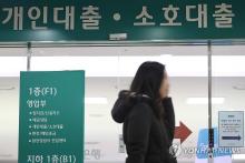 This undated file photo shows a woman walking past a bank promoting its mortgage loan products in Seoul. (Yonhap)