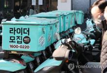 This undated file photo shows a man passing by Baemin riders' motorcycles in Seoul. (Yonhap)