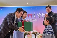 President Lee Jae Myung (L), alongside his wife, Kim Hea Kyung, offers a present to a child patient at Severance Hospital in Seoul on Dec. 24, 2025, in this photo captured from Lee's Instagram page. (PHOTO NOT FOR SALE) (Yonhap)