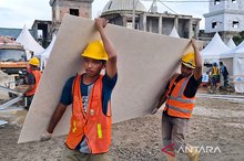 Workers carry building materials at a construction site for 600 temporary houses for flood victims in Aceh Tamiang, Aceh.
