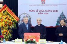 Standing Deputy Prime Minister Nguyen Hoa Binh (left) presents a X-mas gift to the Central Committee for Solidarity of Vietnamese Catholics on December 22. (Photo: VNA)