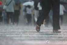 People walk near Gwanghwamun Square in Seoul on July 17, 2024, when a heavy rain alert was issued across the greater Seoul region for the first time this year. (Yonhap)