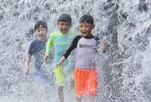 Children enjoy a water fountain at a park in Suwon on Aug. 4, 2024, as heat wave warnings are in effect across the country. (Yonhap)