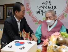 Prime Minister Han Duck-soo (L) congratulates independence fighter Oh Seong-gyu on his 101st birthday at a veterans' nursing home in Suwon, some 30 kilometers south of Seoul, on Aug. 21, 2024. (Yonhap)