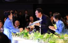 South Korean Olympic table tennis medalist Jeon Ji-hee (L) presents President Yoon Suk Yeol (C) with the Paris Olympic torch signed by South Korean athletes during a dinner hosted by the presidential office at a hotel in Seoul on Aug. 22, 2024, in this photo provided by the office. (PHOTO NOT FOR SALE) (Yonhap)