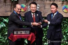 President Yoon Suk Yeol (C) and Chey Tae-won (R), chairman of the Korea Chamber of Commerce and Industry, who will serve as the chair of the 2025 APEC CEO Summit, receive the gavel from Fernando Zavala (L), chair of the 2024 APEC CEO Summit held at the Grand National Theater in Lima, Peru, on Nov. 15, 2024. (local time)(Yonhap)