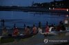 People dip their feet in seawater to cool off on a beach of the southern Jeju Island on July 1, 2025. (Yonhap)